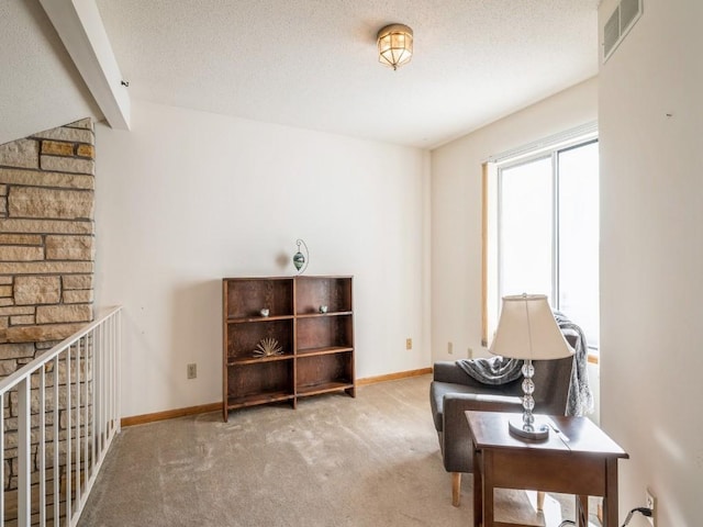 living area with light colored carpet and a textured ceiling