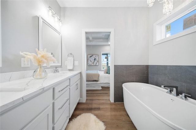 bathroom featuring hardwood / wood-style flooring, vanity, tile walls, and a washtub