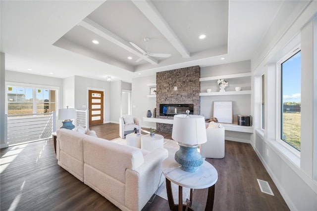 living room featuring beam ceiling, a fireplace, dark hardwood / wood-style floors, and ceiling fan