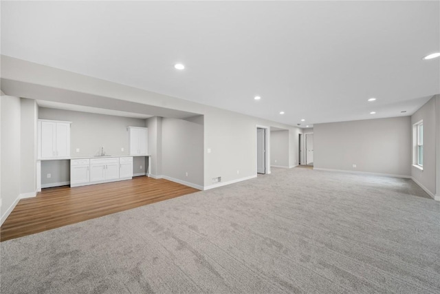 unfurnished living room with sink and light carpet