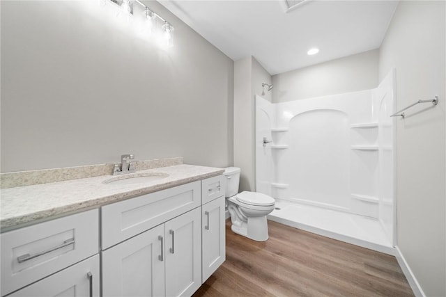 bathroom featuring hardwood / wood-style flooring, walk in shower, vanity, and toilet