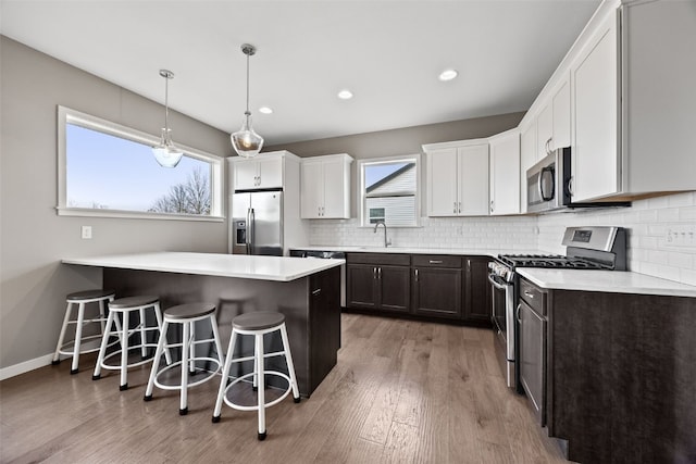 kitchen with sink, a breakfast bar area, tasteful backsplash, stainless steel appliances, and white cabinets