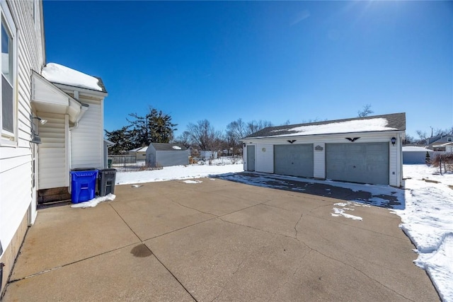 snow covered patio featuring a detached garage and an outdoor structure