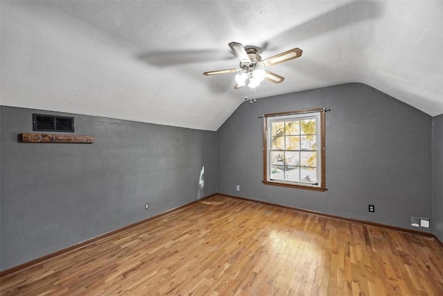 additional living space with ceiling fan, lofted ceiling, a textured ceiling, and light hardwood / wood-style floors