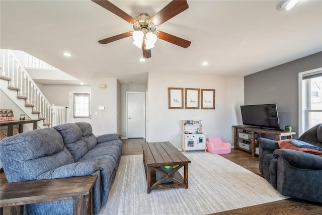 living room featuring dark wood-type flooring, ceiling fan, and plenty of natural light