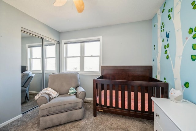 bedroom with ceiling fan, carpet flooring, a closet, and a crib