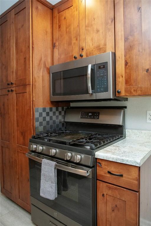 kitchen with tasteful backsplash, light tile patterned floors, and appliances with stainless steel finishes