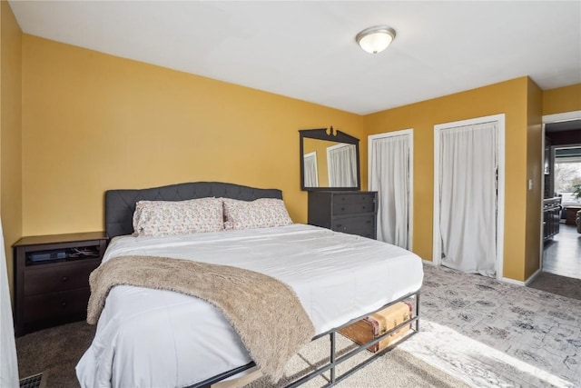 bedroom featuring multiple closets, carpet flooring, visible vents, and baseboards