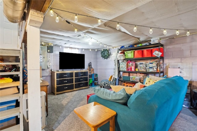 carpeted living area with concrete block wall