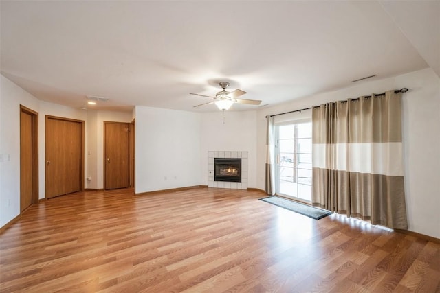 unfurnished living room with a tile fireplace, ceiling fan, and light hardwood / wood-style flooring