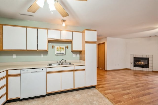 kitchen with sink, white cabinets, white dishwasher, and a fireplace