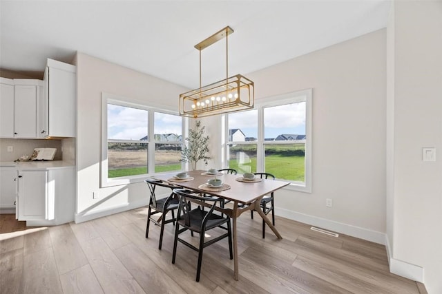 dining space with an inviting chandelier and light hardwood / wood-style floors