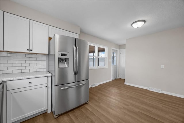 kitchen with backsplash, appliances with stainless steel finishes, light wood-type flooring, and white cabinets