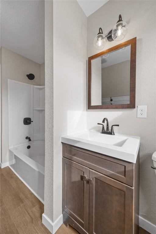 bathroom featuring hardwood / wood-style flooring,  shower combination, and vanity