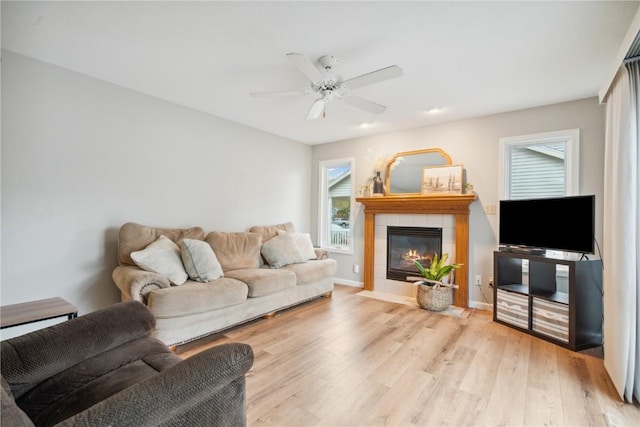 living room featuring ceiling fan, a fireplace, and light wood-type flooring