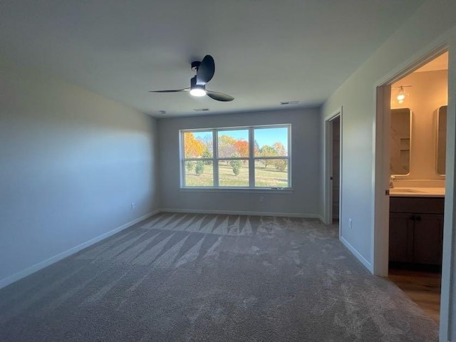 empty room featuring dark colored carpet, sink, and ceiling fan