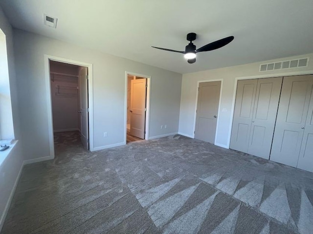 unfurnished bedroom with dark carpet, ensuite bath, a closet, and ceiling fan