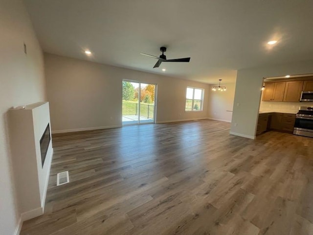 unfurnished living room with hardwood / wood-style floors and ceiling fan with notable chandelier