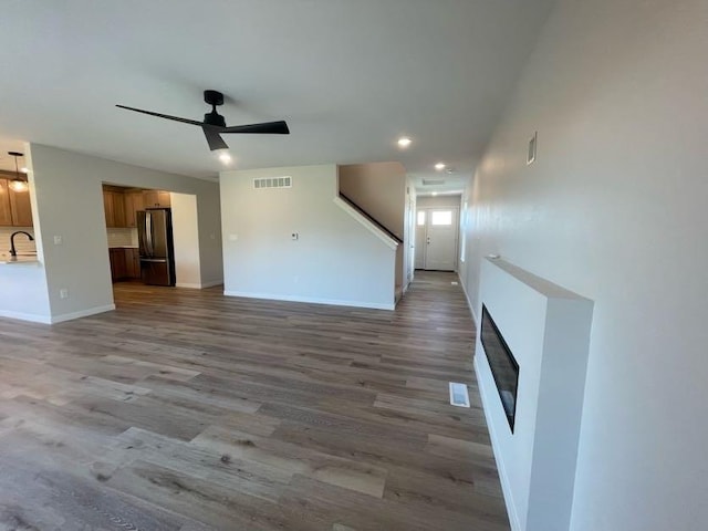 unfurnished living room with sink, ceiling fan, and light hardwood / wood-style flooring