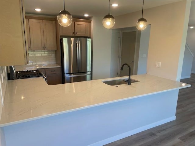 kitchen with pendant lighting, stainless steel fridge, kitchen peninsula, and sink