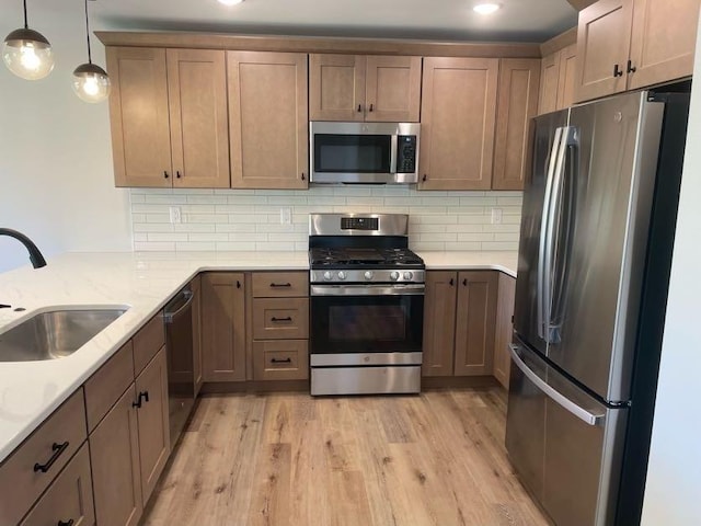 kitchen featuring sink, light hardwood / wood-style flooring, appliances with stainless steel finishes, backsplash, and decorative light fixtures