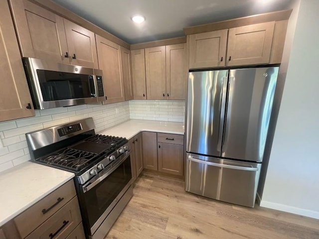 kitchen featuring appliances with stainless steel finishes, backsplash, and light wood-type flooring