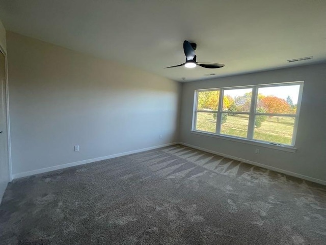 unfurnished room with ceiling fan and dark colored carpet