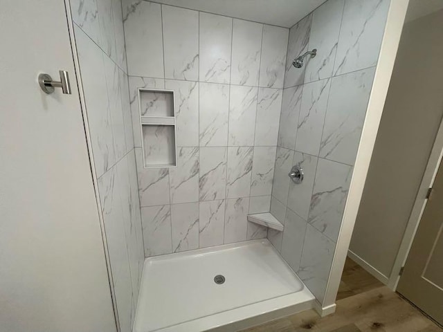 bathroom featuring wood-type flooring and tiled shower