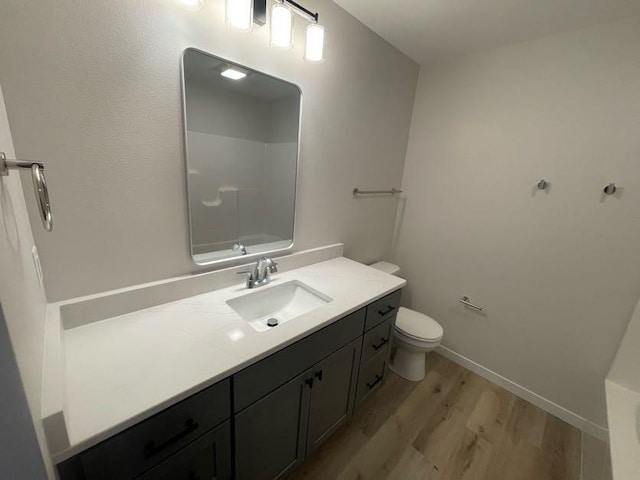 bathroom featuring vanity, hardwood / wood-style flooring, toilet, and walk in shower