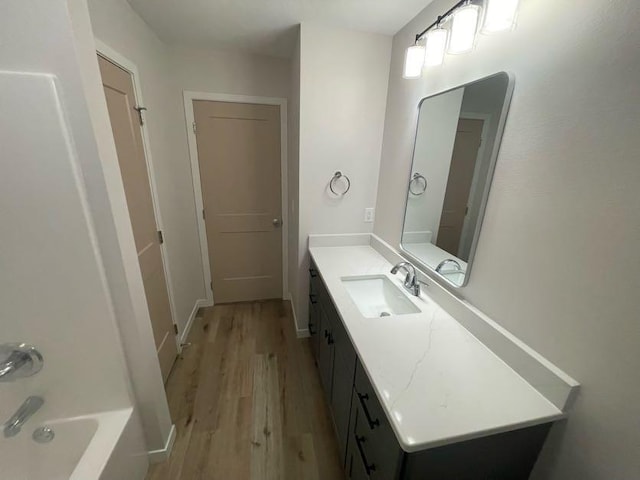 bathroom with hardwood / wood-style flooring, vanity, and tub / shower combination