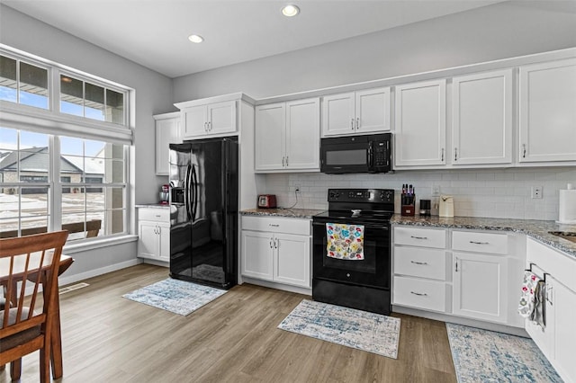 kitchen featuring black appliances, light hardwood / wood-style floors, white cabinets, and stone countertops