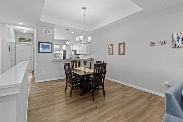 dining room with a tray ceiling and wood-type flooring