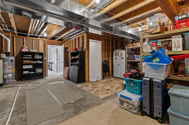 basement featuring water heater and white refrigerator