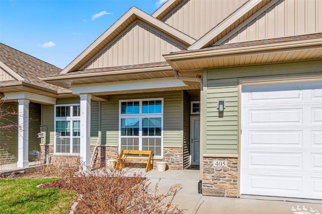 405 Ridge View Dr, West Branch, IA 52358 - entrance to property featuring stone siding, board and batten siding, a porch, and an attached garage