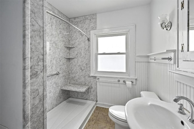 bathroom with tile patterned flooring, toilet, sink, and tiled shower