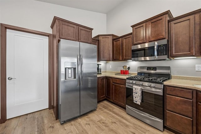 kitchen featuring stainless steel appliances, dark brown cabinetry, and light wood-type flooring