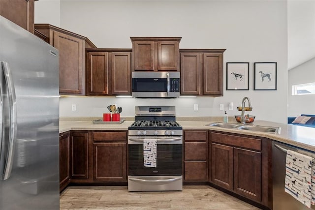 kitchen with appliances with stainless steel finishes, sink, and light hardwood / wood-style floors