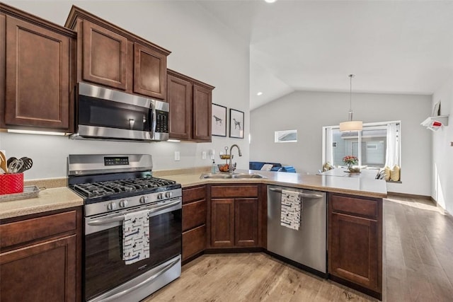 kitchen with sink, vaulted ceiling, pendant lighting, stainless steel appliances, and light hardwood / wood-style floors