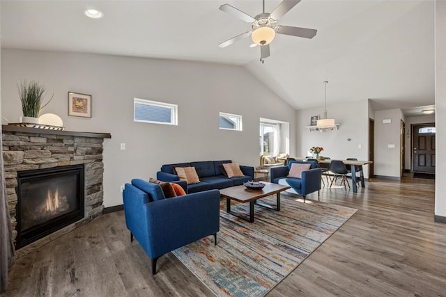 living room with wood-type flooring, high vaulted ceiling, ceiling fan, and a fireplace