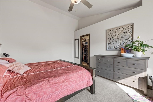 carpeted bedroom featuring vaulted ceiling, a walk in closet, ceiling fan, and a closet