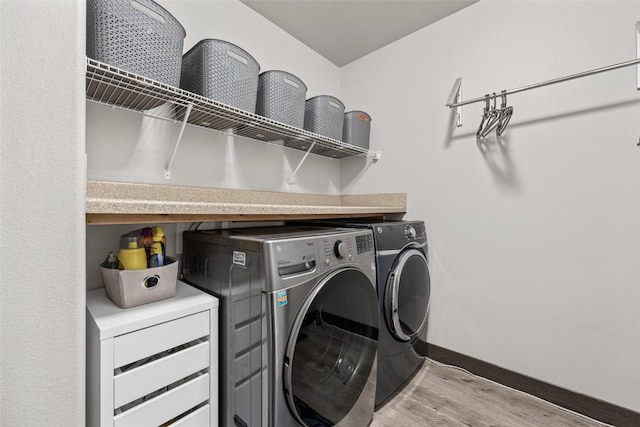 clothes washing area with light wood-type flooring and washer and clothes dryer