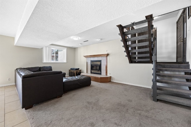 living room with a tiled fireplace, tile patterned floors, and a textured ceiling