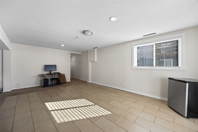 unfurnished living room featuring a textured ceiling and light tile patterned floors