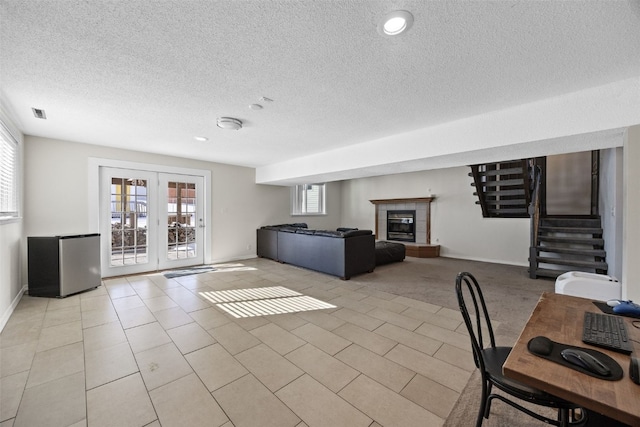 unfurnished living room with french doors, light tile patterned flooring, a tile fireplace, and a wealth of natural light