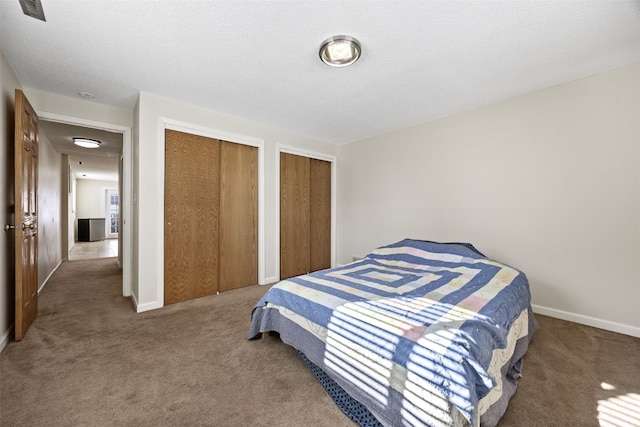 carpeted bedroom with multiple closets and a textured ceiling