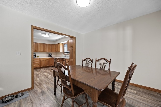 dining area with light hardwood / wood-style flooring and a textured ceiling