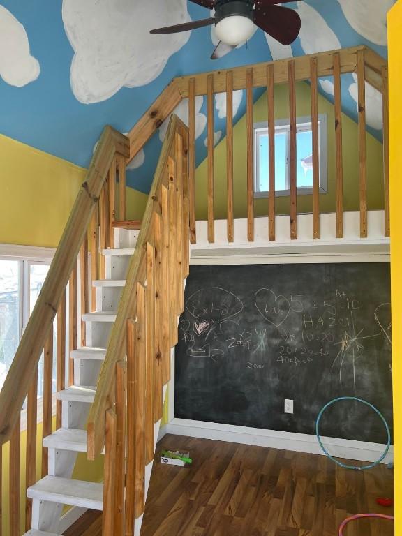 stairs featuring vaulted ceiling, hardwood / wood-style floors, and ceiling fan