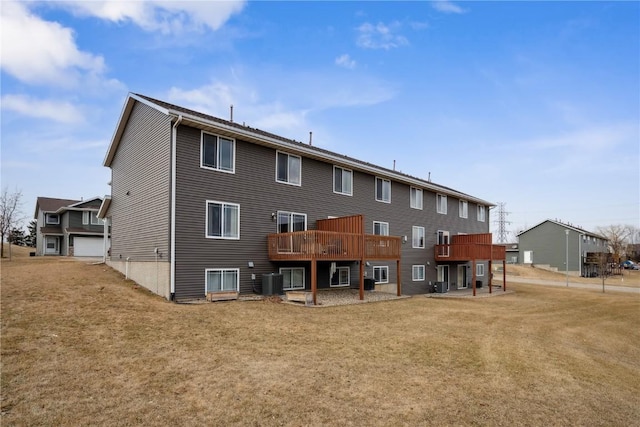 rear view of house with a wooden deck, cooling unit, and a lawn