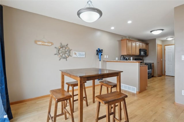 kitchen with electric stove, kitchen peninsula, light hardwood / wood-style flooring, and light brown cabinets