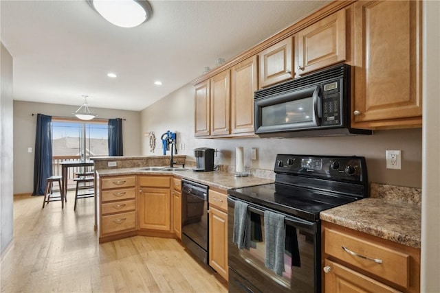 kitchen with black appliances, sink, hanging light fixtures, kitchen peninsula, and light hardwood / wood-style flooring